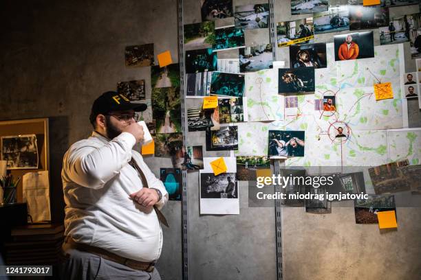 fbi detective looking at city map with photographs on wall and trying to solve the case - photo wall stock pictures, royalty-free photos & images