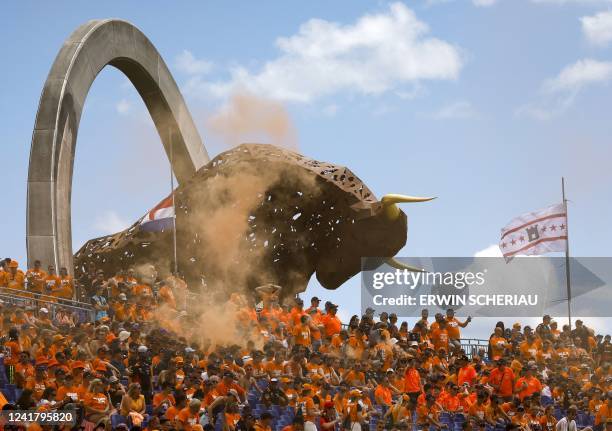 Supporters of Red Bull Racing's Dutch driver Max Verstappen cheer from the stands near the large-scale jumping bull sculpture during the second...