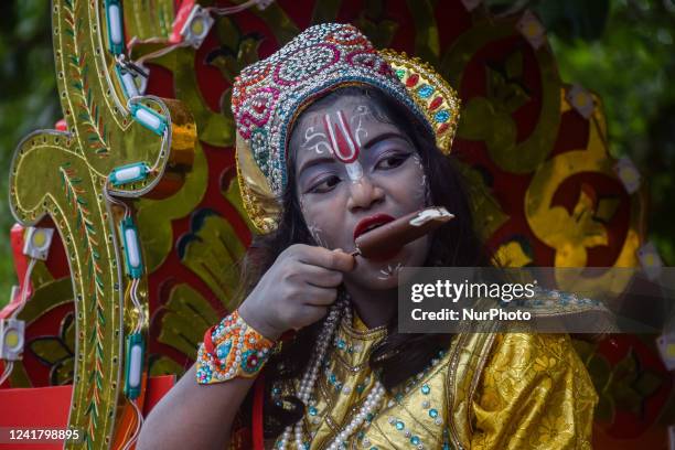 Girl, dressed as Hindu god Krishna, eats ice cream during the concluding ceremony of Jagannath Rath Yatra 2022, in Kolkata on July 09 2022. The...