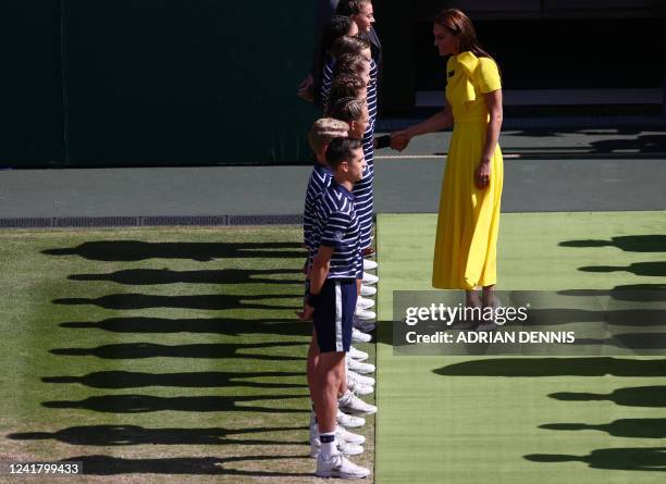 Britain's Catherine, Duchess of Cambridge, shakes hands with ball boys and girls as she arrives on centre court for the trophy ceremony after...