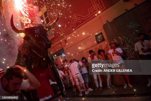 Man wearing a costume of "Toro de Fuego" chases people during the San Fermin Festival in Pamplona, northern Spain, on July 9, 2022.