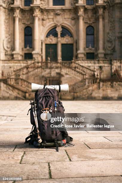 pilgrim's backpack resting on the ground in front of the cathedral of santiago de compostela. - santiago foto e immagini stock