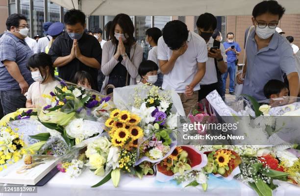 People pray after placing flowers at a makeshift memorial in Nara, western Japan, on July 10 near the scene where former Japanese Prime Minister...