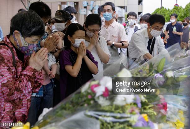 People pray after placing flowers at a makeshift memorial in Nara, western Japan, on July 10 near the scene where former Japanese Prime Minister...