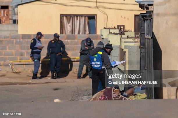 Members of the South African Police Service and forensic pathology service inspect the scene of a mass shooting in Soweto, South Africa, on July 10,...