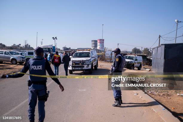 South African Police Service officers enforce a perimeter around a crime scene as pathalogical investigators inspect the crime scene where 14 people...