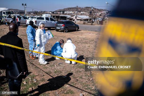 South African Police Service officers enforce a perimeter around a crime scene as pathalogical investigators inspect the crime scene where 14 people...