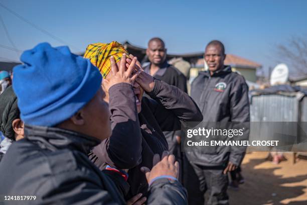 Relative of one of the 14 victims shot dead in a tavern in Soweto reacts next to the crime scene in Soweto on July 10, 2022. - Fourteen people were...