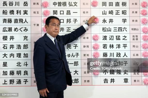 Japan's Prime Minister and the President of the Liberal Democratic Party Fumio Kishida places a red paper rose on a LDP candidate's name to indicate...