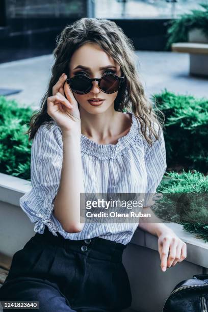 a young woman in a striped shirt holds half glasses down - down blouse ストックフォトと画像