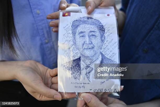 Couple show an image representing the portrait of Shinzo Abe as they came pay homage in front of the residence of dead former Prime Minister of Japan...