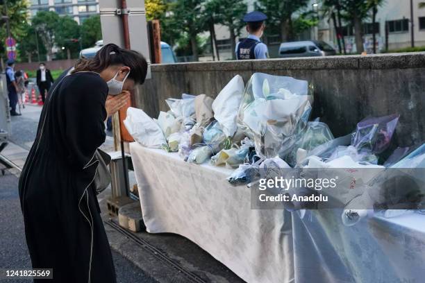 Mourner offers a flower near the entrance of the Liberal Democratic Party headquarters building in Tokyo, Japan, on Sunday, July 10, 2022.