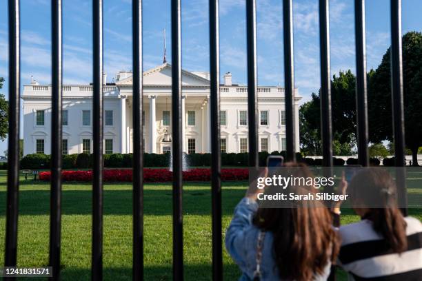 Two people take photos of the White House from Lafayette Park on July 10, 2022 in Washington, DC.