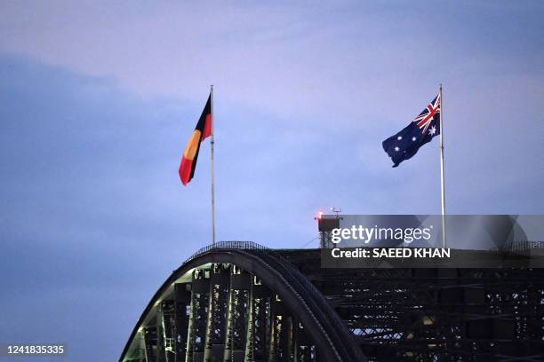 Australia's black, red and yellow Aboriginal flag flies beside Australia's national flag over the Harbour Bridge in Sydney on July 11, 2022. The...