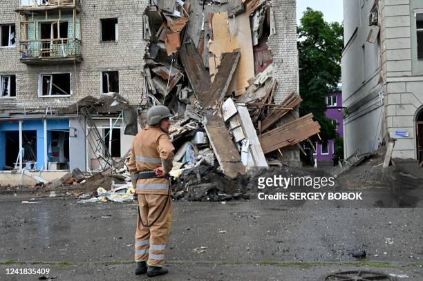 Ukrainian rescuer stands next to a building partially destroyed after a Russian missile strike in Kharkiv on July 11 amid Russia's military invasion...