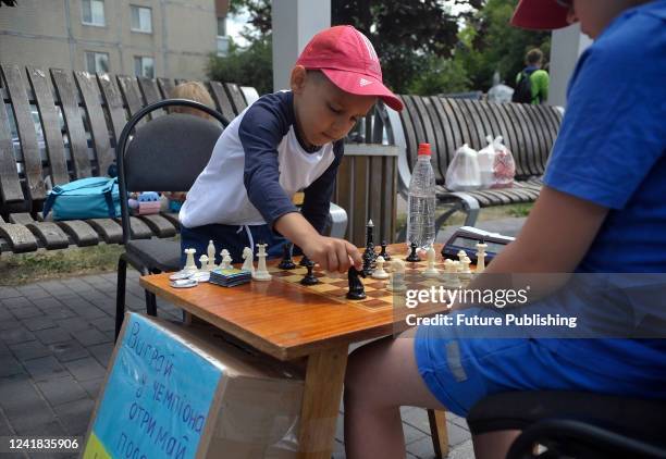 Five-year-old chess prodigy Artem Kucher makes a move against a boy during a charity chess match in support of the Ukrainian Armed Forces in...