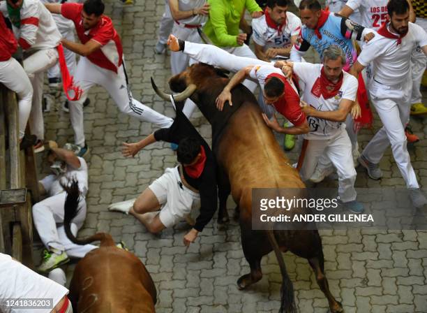 Participants fall down next to Jose Cebada Gago bulls during the fifth "encierro" of the San Fermin festival in Pamplona, northern Spain on July 11,...