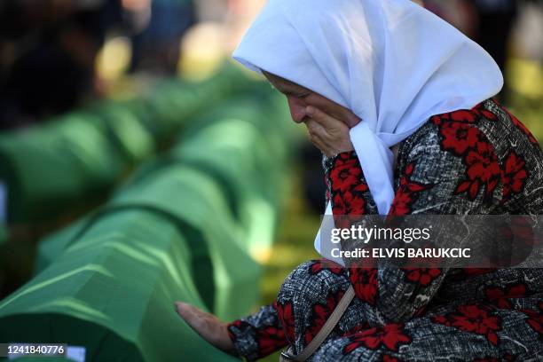 Bosnian Muslim woman, a survivor of the 1995 Srebrenica massacre, mourns near the caskets containing remains of her relatives, at the memorial...