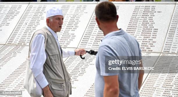 Bosnian Muslims pass by the memorial wall during a mass burial of victims of the 1995 Srebrenica massacre, at the memorial cemetery in the village of...