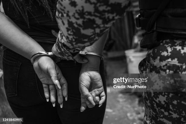 Police officer escorts a handcuffed suspect while taking part in a house by house operative while searching for an alleged gang member on July 6,...