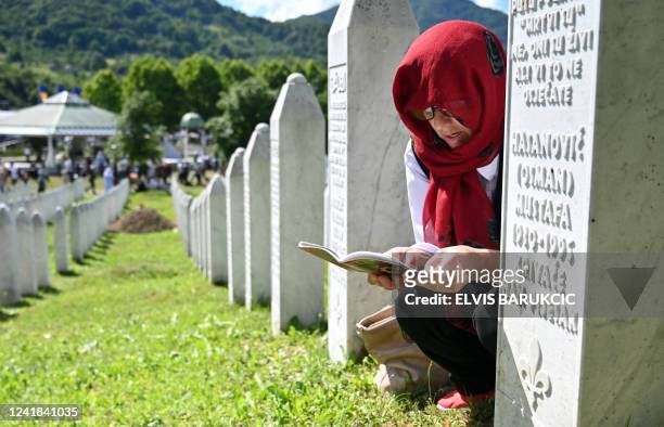 Bosnian Muslim woman, a survivor of the 1995 Srebrenica massacre, reads from an Islamic prayer book near the graves of her relatives, at the memorial...