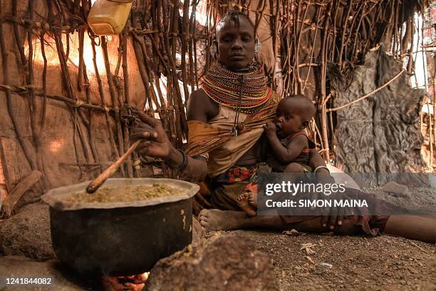 Woman breastfeeds her child inside her makeshift house while cooking at the Parapul village, in Loiyangalani area hosting families affected by the...