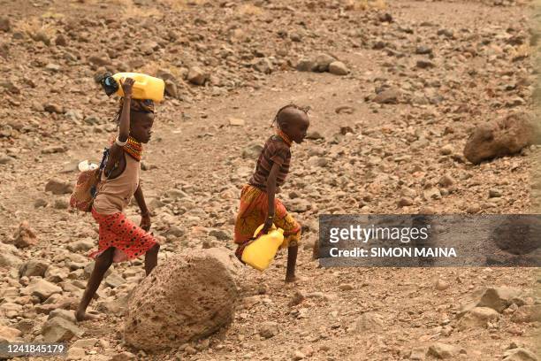 Young Turkana girls carry jerrycans of water on a rocky hill in the Loiyangalani area where families affected by the prolonged drought are hosted, at...