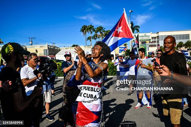 Man bound by a chain shouts slogans as he marches through the streets of Miami, Florida, to commemorate last year's historic protests in Cuba, on...