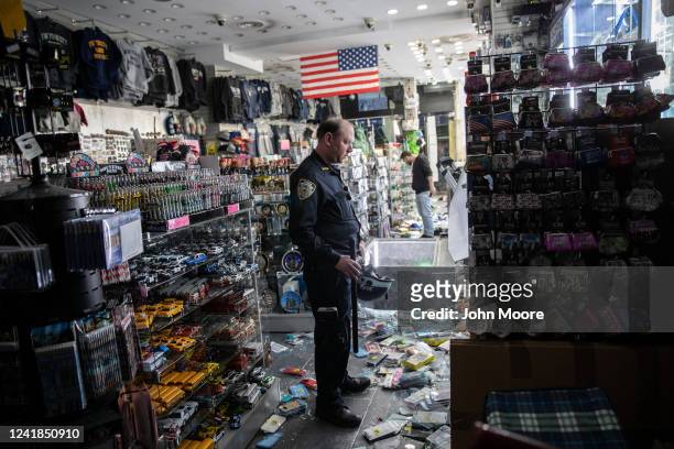 New York City police officer stands guard in a looted souvenir and electronics shop near Times Square after a night of protests and vandalism over...