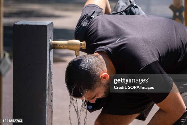 Man is refreshing his head with water in a public fountain on the Barceloneta pier. The second wave of extreme heat may exceed 44 degrees Celsius in...