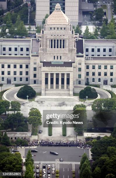 The vehicle carrying the coffin of former Japanese Prime Minister Shinzo Abe passes in front of the parliament building in Tokyo on July 12 following...
