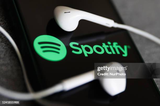 Spotify logo displayed on a phone screen and headphones are seen in this illustration photo taken in Krakow, Poland on July 12, 2022.