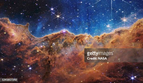 In this handout photo provided by NASA, a landscape of mountains and valleys speckled with glittering stars is actually the edge of a nearby, young,...