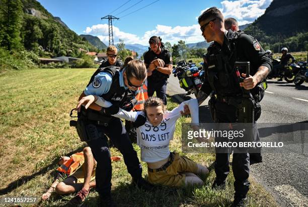 French gendarmes remove environmental protestors of the movement "Derniere Renovation" from the race route as their protest action temporarily...