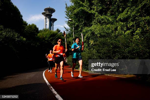People run with the Olympic torch at the Olympic Forest Park on July 13, 2022 in Beijing, China. China is commemorating the 21st anniversary of the...