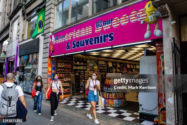 Shoppers pass in front of an American sweet and souvenir shop on Oxford Street on 11th July 2022 in London, United Kingdom. Numerous American 'candy'...