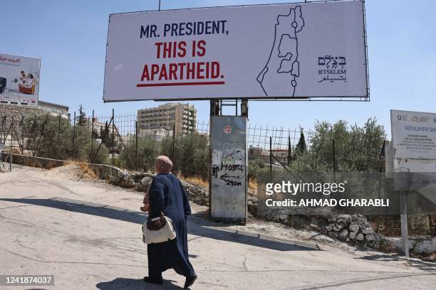 Woman walks past a billboard, part of a campaign organised by Israeli rights group B'Tselem, in the West Bank biblical city of Bethlehem on July 13...