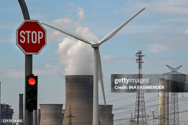 Stop sign and a wind turbine are seen in front of a coal-fired power plant operated by German energy supplier RWE in Niederaussem, western Germany,...