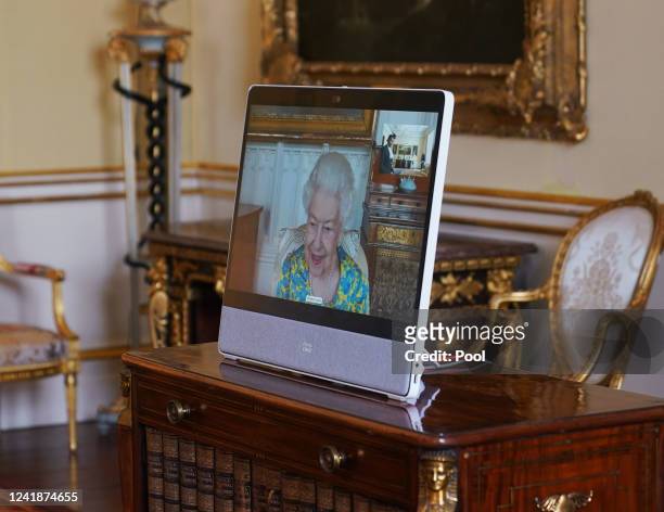 Queen Elizabeth II, in residence at Windsor Castle, appears on a screen via videolink, during a virtual audience to receive Thandazile Mbuyisa, High...