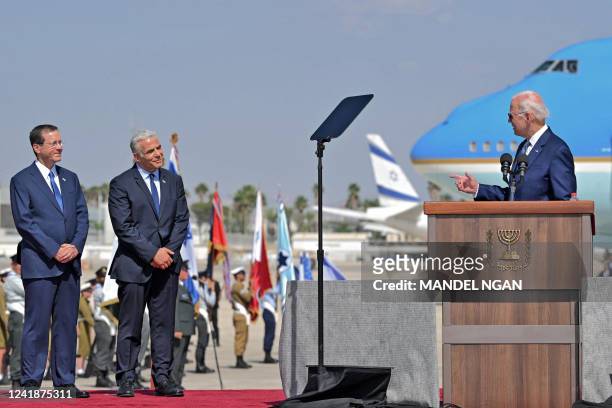 Israel's President Isaac Herzog and caretaker Prime Minister Yair Lapid listen to US President Joe Biden as he addresses his hosts upon his arrival...