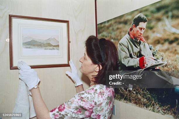 Picture taken on June 25, 1996 at the Sotheby's Gallery at London showing an employee hanging a watercolour made by Britain's Prince Charles as part...