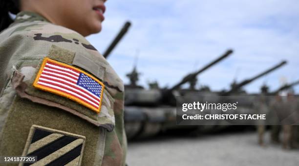 Badge of the US flag is seen on the uniform of a female US soldier as she stands near tanks at the United States Army military training base in...