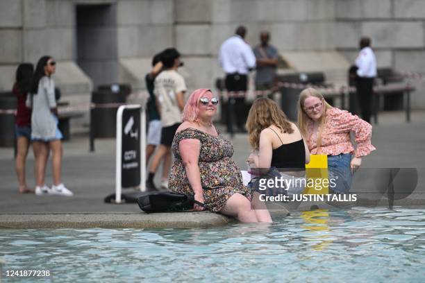 Pedestrians cool off with their feet in the water of the Trafalgar Square fountain, in central London, on July 13 during a heatwave. - Britain...