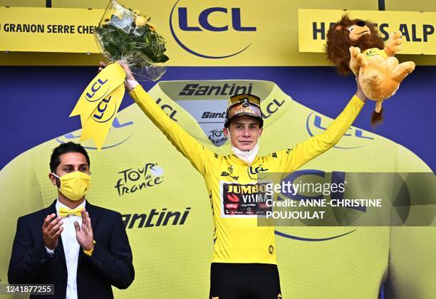 Jumbo-Visma team's Danish rider Jonas Vingegaard celebrates on the podium with the overall leader's yellow jersey after the 11th stage of the 109th...