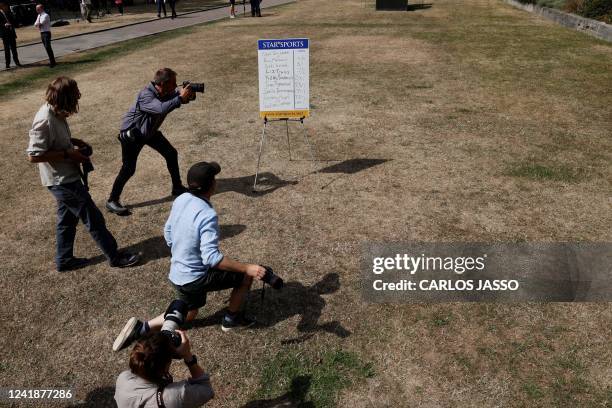 Photographers take pictures of a board reading the latest odds result for the candidates vying to succeed Britain's Prime Minister, outside the...