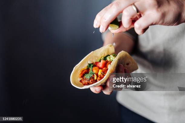 la mano femminile stringe la calce in tacos vegani - cucina messicana foto e immagini stock