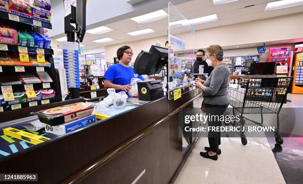 People stand at the check-out counter after shopping at a grocery supermarket in Alhambra, California, on July 13, 2022. US consumer price inflation...