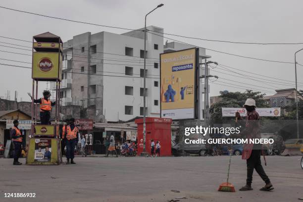 Kinshasa city sanitation officer sweeps the street next to a traffic police station in the Democratic Republic of Congo, on July 6, 2022.