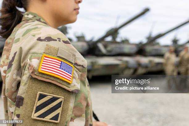 July 2022, Bavaria, Grafenwöhr: A female U.S. Army soldier of the 1st Brigade of the 3rd Infantry Division stands in front of tanks during a visit by...