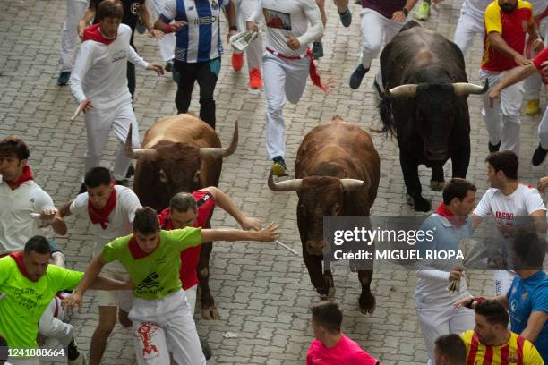 Participants run ahead of Miura bulls during the "encierro" of the San Fermin festival, in Pamplona, northern Spain on July 14, 2022. On each day of...